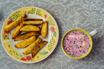 A bowl of popular Lithuanian cold beetroot soup Saltibarsciai with baked potato wedges
