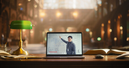Asian Male Presenting Business Strategy on a Laptop Screen, Surrounded by Books in a Classical...