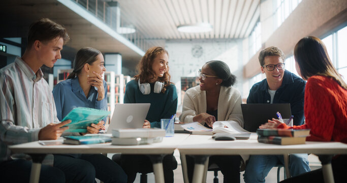 Diverse Group of Students Engaged in a Study Session at a Modern Library. Young Adults Collaborating Over Books and Laptops, Sharing Ideas and Learning Together in a Collegiate Environment.
