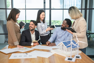 smiling young multiracial business people discuss in office room,meeting engineers or architect a new home project,renewable energy,solar energy and wind turbine technology
