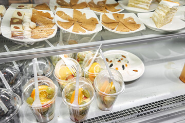 Display case showcasing a variety of desserts and fruit cups