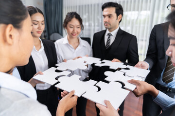 Multiethnic business people holding jigsaw pieces and merge them together as effective solution...