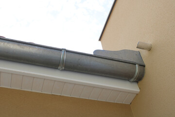 Gouttière zinc gris sur la façade de la maison, descentes et lambris de sous-face en PVC blanc 