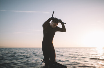 Young man in wetsuit put on a diving mask and snorkel and prepare for a dive