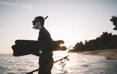 Young spearfisherman holds fins and spear gun and ready for spearfishing