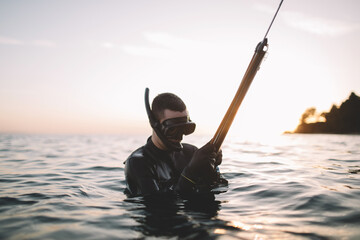 Young active man prepare speargun for fish hunting