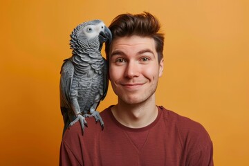 grey jaco pet parrot sitting on a man’s shoulder, portrait of male with domestic african parakeet on plain background