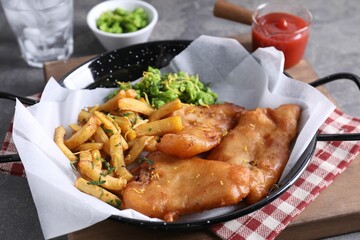 Tasty fish, chips, sauce and peas on grey table, closeup