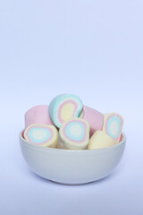 Colorful marshmallows in a bowl on a white background.