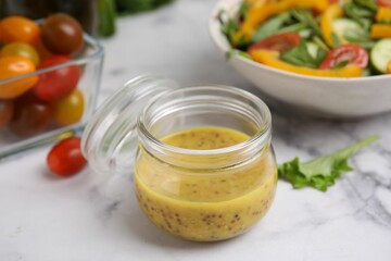 Tasty vinegar based sauce (Vinaigrette) in jar on white marble table, closeup