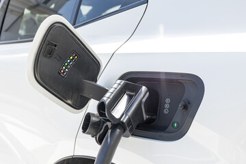 charging EV car electric vehicle clean energy for driving future. close-up shot in sunny blue sky background