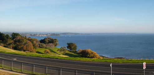 Elevated panoramic view of a country highway along the beautiful coastline with the rural scenery of farmland and bass strait, San Remo, VIC Australia.