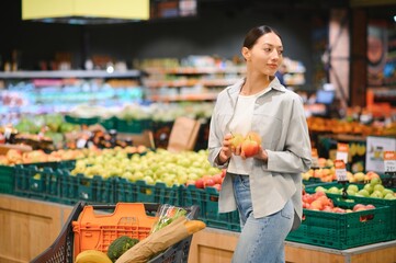 young adult woman choosing apples in grocery store. lifestyle