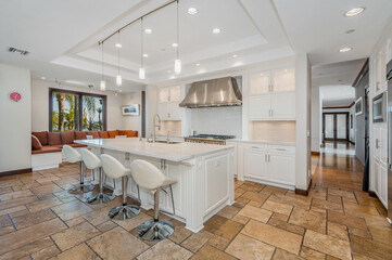 a kitchen has a huge center island with chairs and marble counter tops