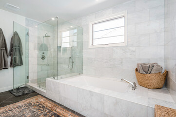a bathtub sitting next to a bathroom filled with white marble tiles