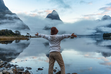 Female tourist enjoying with the Milford sound with Mitre peak and foggy on the lake view at New...