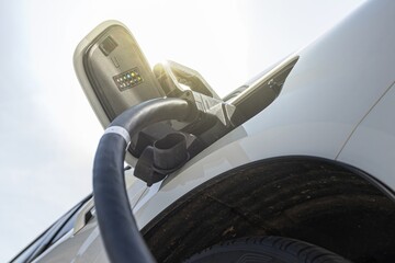 Electric car in EV charging station with sunlight in the background, concept of green energy and...