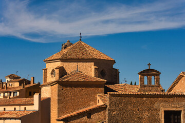 Obraz premium The rooftops of medieval houses and the dome of a church in the city of Cuenca, Spain, against a backdrop of blue sky