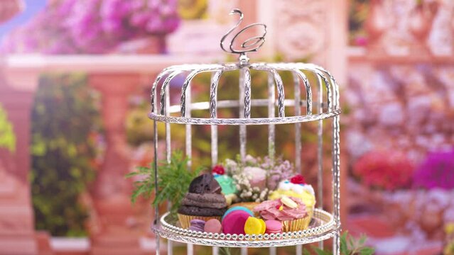 Afternoon Tea or High Tea Display in the silver rack with flowers, macaron, scone, cake, cup cakes, on colorful background