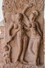 Two women with child standing on stone relief. 7th century temples, Pattadakal, India. UNESCO World Heritage site.
