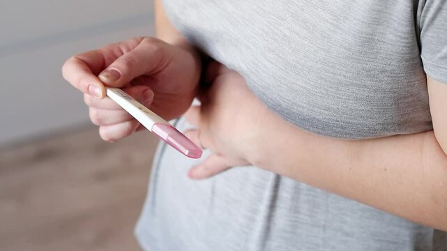 Close up top view of a woman holding a positive pregnancy test