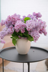 Bouquet of Lilacs in a Ceramic Vase on black coffee table. Branch with Spring Lilac Flowers.