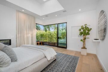 a bedroom with white walls, a fireplace and floor to ceiling windows