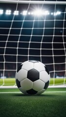 A classic black and white soccer ball sits just inside the goal line against the backdrop of a vivid green field and a net, capturing a pivotal game-winning moment. Vertical shot
