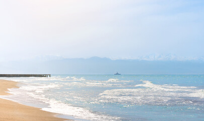 Seascape. A ship sails on the sea against a backdrop of mountains