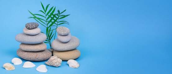 Two stone pyramids are being built next to palm leaves and seashell on a blue background. Summer...