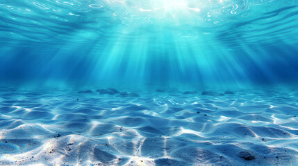 Underwater seascape with sun rays penetrating clear blue water and illuminating a sandy bottom.