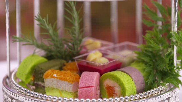 Afternoon Tea or High Tea Display in the silver rack with flowers, macaron, scone, cake, cup cakes, on colorful background