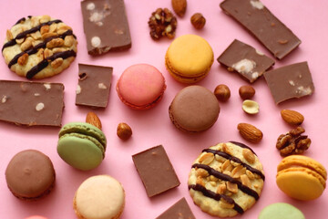 Pastel macarons, almond chocolate, peanut butter cookies and various nuts on bright pink background. Selective focus.