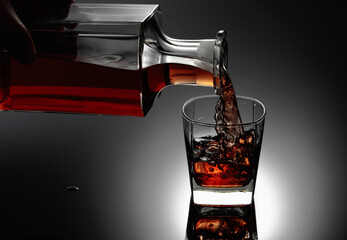  Whiskey is poured from a decanter into a frozen glass with natural ice.