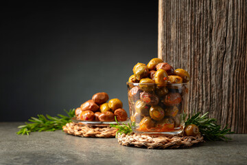 Spicy olives in a glass bowl on a stone table.
