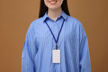 Woman with blank badge on brown background, closeup