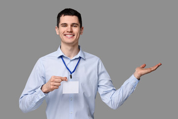 Smiling man with empty badge showing something on grey background