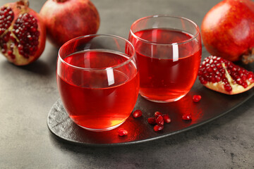 Tasty pomegranate juice in glasses and fresh fruits on grey table