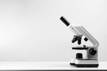 Modern microscope on white table, space for text
