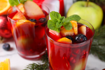 Aromatic Sangria drink in glasses, ingredients and Christmas decor on white marble table, closeup