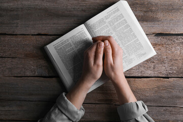 Naklejka premium Religion. Christian woman praying over Bible at wooden table, top view