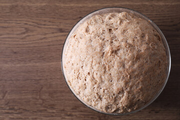 Fresh sourdough in bowl on wooden table, top view. Space for text