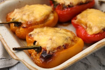 Delicious stuffed bell peppers in baking dish on table, closeup