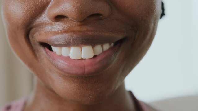 Portrait of young black woman with imperfect shape in sportswear doing workout at home. She is beginner in sports, doing training exercises. Skin is covered by sweat. She smiles and feels contented