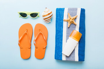 Summer holiday concept. Top view of beach towel, flip flop and sunscreen cream on table Top view...