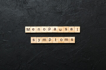 menopausal symptoms word written on wood block. menopausal symptoms text on cement table for your...