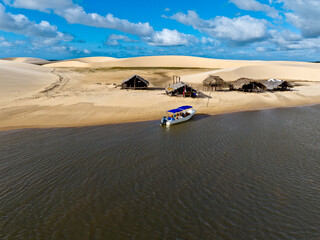 Aerial view of Parque da Dunas - Ilha das Canarias, Brazil. Huts on the Delta do Parnaíba and Delta das Americas. Lush nature and sand dunes. Boats on the river bank
