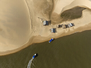 Aerial view of Parque da Dunas - Ilha das Canarias, Brazil. Huts on the Delta do Parnaíba and Delta das Americas. Lush nature and sand dunes. Boats on the river bank

