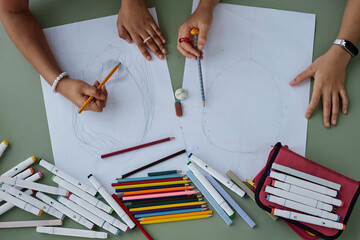 Top view two unrecognizable Black girls drawing pictures together at table, copy space