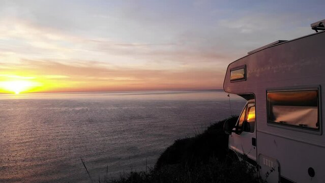Aerial view. Sunrise over sea horizon and camper rv camping on beach seashore. Holidays in Spain, travel with motor home.